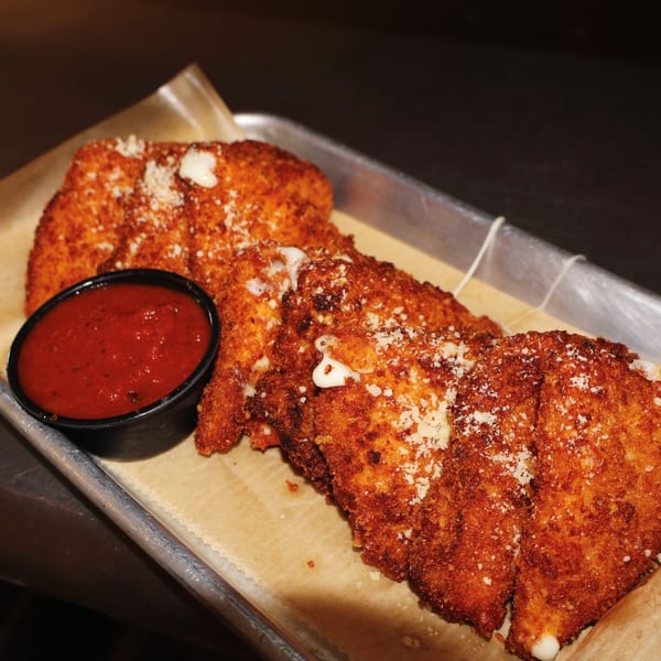 Golden-brown fried mozzarella sticks with melted cheese and a side of marinara sauce.