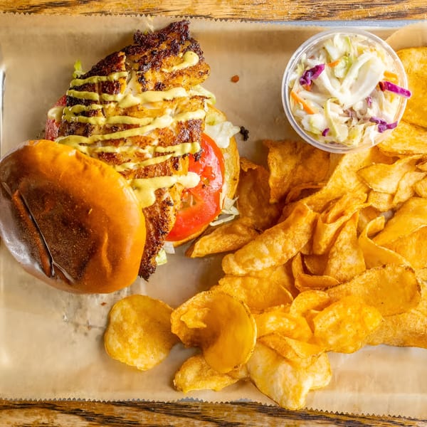 Charm City Seafood's blackened fish sandwich with coleslaw and potato chips on a tray.